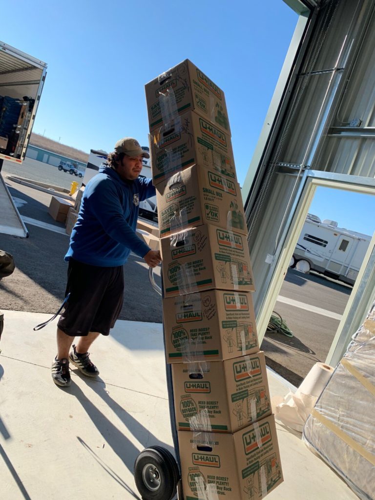 ASAP Movers crew member wheeling a tall stack of boxes on a hand truck